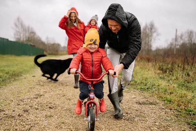 Parent helping toddler prepare for their first bike ride with safety gear